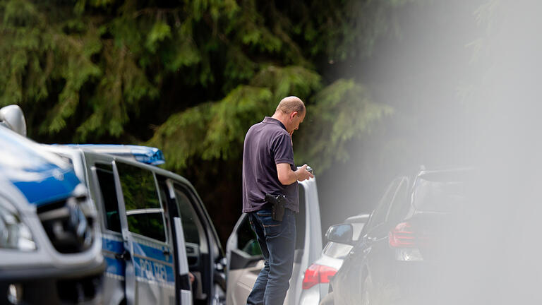 Skelettteile entdeckt - Suche       -  Ein Mitarbeiter der Polizei steht am 04.07.2016 am Waldrand an einer Verbindungsstraße zwischen Rodacherbrunn in Thüringen und Nordhalben in Bayern. Nach dem Fund einer Leiche in dem Waldstück prüfen die Ermittler Verbindungen zum Fall der vor mehr als 15 Jahren verschwundenen Peggy aus Oberfranken. Der Fundort der Leiche im Saale-Orla-Kreis liegt nur wenige Kilometer von Peggys Heimatort Lichtenberg (Landkreis Hof) entfernt. Foto: Daniel Karmann/dpa +++(c) dpa - Bildfunk+++ | Verwendung weltweit