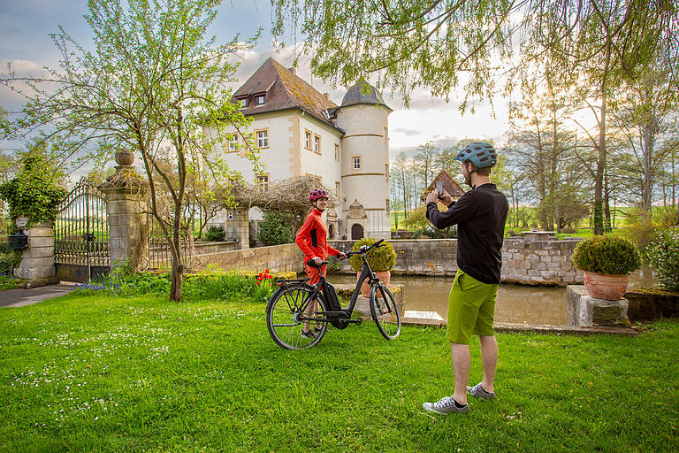 Das Grabfeld mit dem E-Bike entdecken: Mehrere der insgesamt 23 neu markierten Themenrouten starten und enden in Bad Königshofen und führen unter anderem am Wasserschloss in Kleinbardorf vorbei.