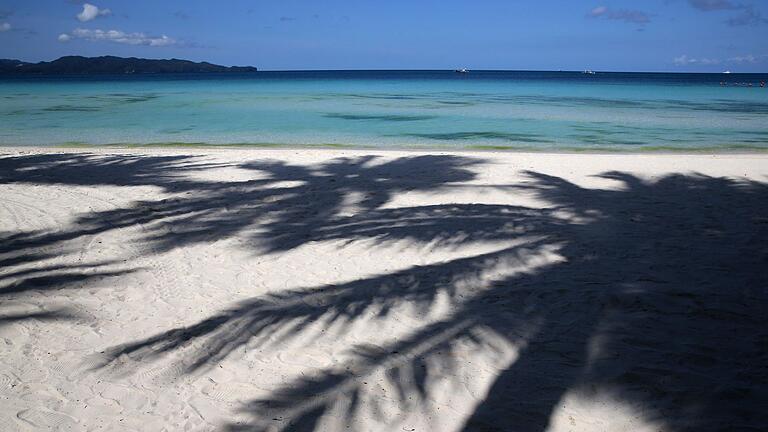 1,3 Kilometer sind nicht &bdquo;wenige Gehminuten&rdquo; zum Strand       -  Palmen werfen Schatten auf den Strand.