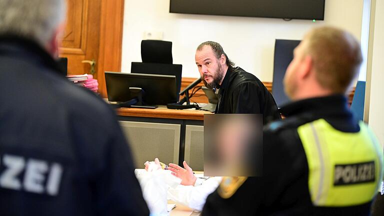 Rechtsanwalt Christian Barthelmes mit dem Angeklagten, im Vordergrund zwei Polizeibeamte