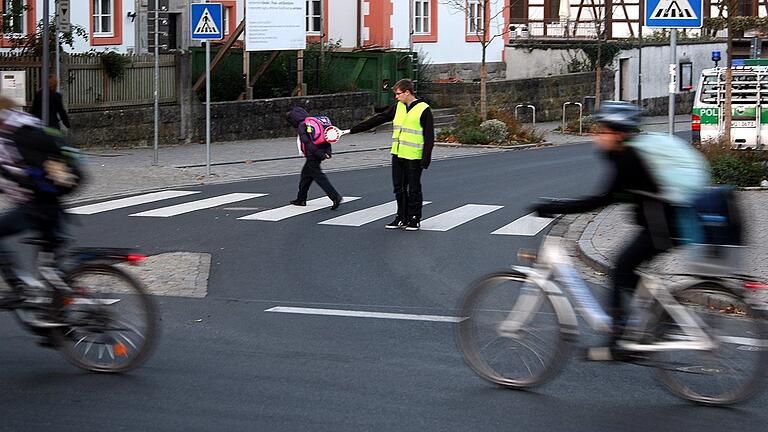 Ein Schülerlotse unterstützt in Hammelburg eine Schülerin bei der Straßenüberquerung