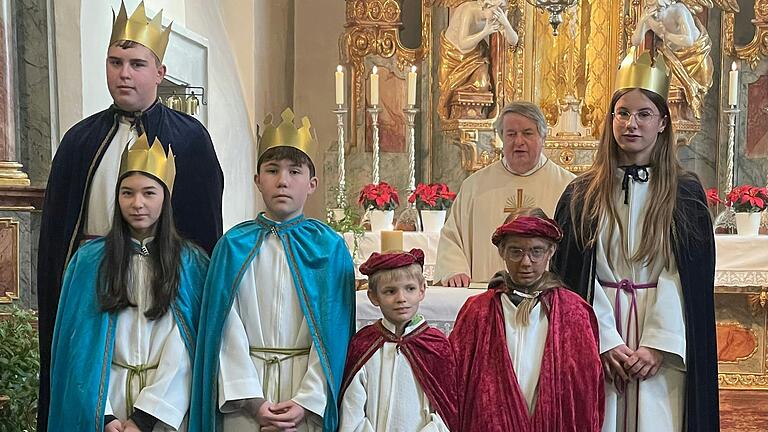 Die Sternsinger in der Kirche. Auf dem Foto von links:  Nico Scheiner, Amy Loder, Bastian Barthel, Korbinian Mayer, Ella Schenk und Eva Scheiner.  Am Altar steht Pfarrer Günter Höfler.