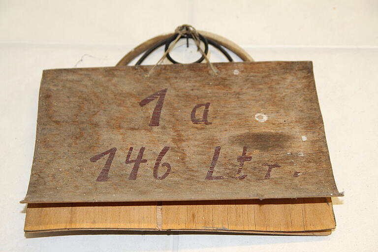 An der Wand des Brennraums von Martha Gehring hängt eine hölzerne Tafel von 1945. 146 Liter Maische fasst der Wasserbadkessel. An der Wand des Brennraums von Martha Gehring hängt eine hölzerne Tafel von 1945. 146 Liter Maische fasst der Wasserbadkessel.