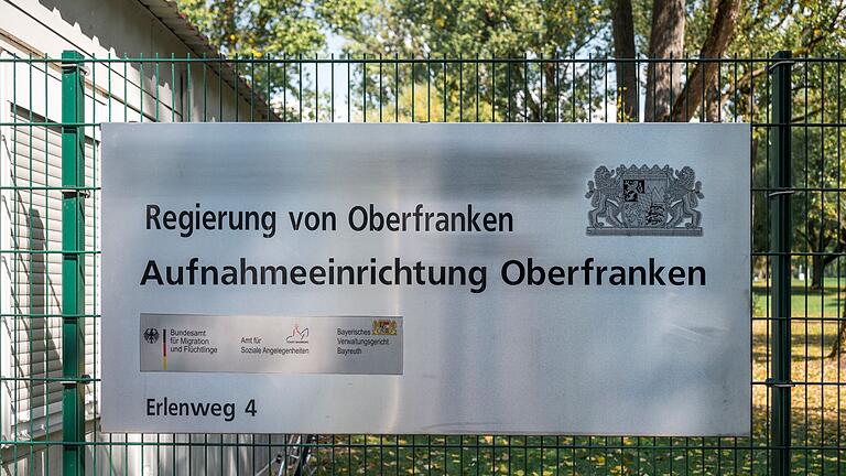 Ankerzentrum Bamberg.jpeg       -  Ein Hinweisschild der Aufnahmeeinrichtung Oberfranken hängt am Zaun der Flüchtlingsunterkunft.