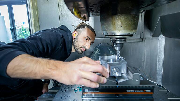 Furkan Gönültunc überprüft einen Rohling und Werkzeug in einer Maschine.