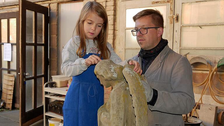 Dominika hat Spaß daran, einen Engel aus grünem Sandstein fachgerecht von Moos und Flechten zu befreien. Ihr Vater Sebastian Hornung zeigt es ihr gern.