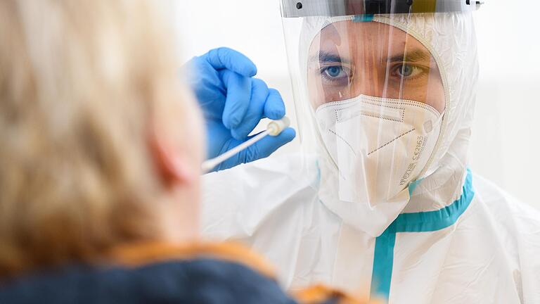 Ein Mitarbeiter in Schutzkleidung demonstriert im Corona Testzentrum an der Talavera in Würzburg die Vorgehensweise bei einem Corona-Test. Ein Mitarbeiter in Schutzkleidung demonstriert im Corona Testzentrum an der Talavera in Würzburg die Vorgehensweise bei einem Corona-Test.