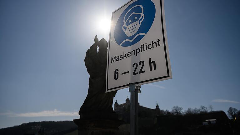 Schilder verweisen auf der Alten Mainbrücke in Würzburg auf die bestehenden Coronaregeln.