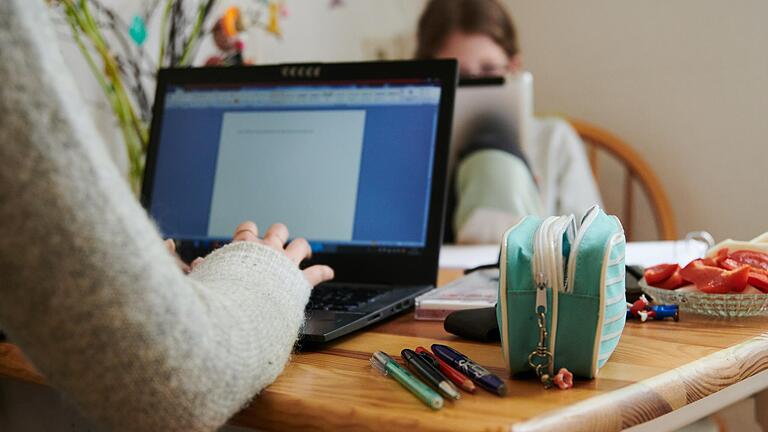 Eine Mutter arbeitet auf diesem Symbolbild am Küchentisch während ihre Tochter gegenüber in ein Tablet schaut. Bei einer Umfrage unter Schweinfurter Schülerinnen und Schülern stellte sich heraus, dass Home-Schooling nicht sonderlich beliebt ist.