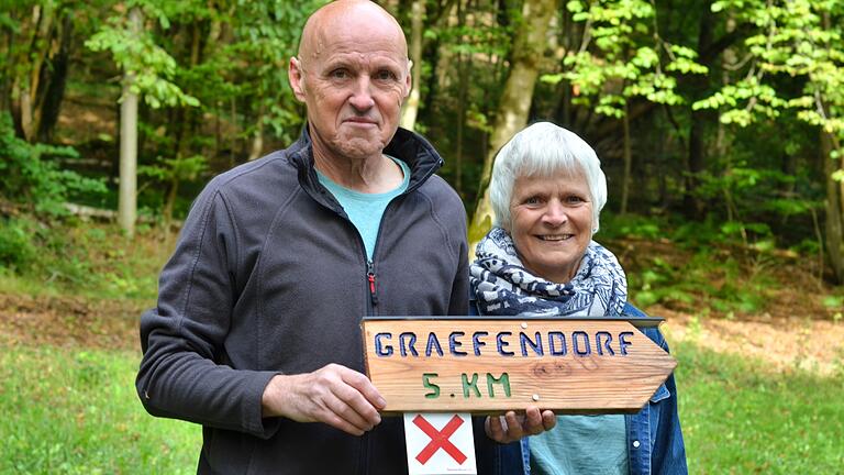 Das Ehepaar Pfeifroth mit einem selbstgemachten Holzschild. Die Schilder stellen die beiden Wegemarkierer selbst her.