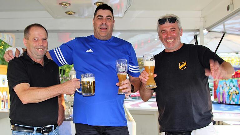 Im Getränkestand des SV Obervolkach stoßen Michael Möslein, Matthias Gabriel und Uwe Feuerbach (von links) mit Bier auf das Weinfest an.