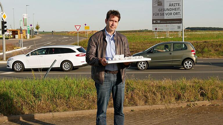 Der Zahnmediziner und Oralchirurg Dr. Etienne Loho mit dem Modell des 'Medical Center Windmühle'. Im Hintergrund ist das Gelände zu sehen, auf dem das medizinische Zentrum einmal stehen wird.