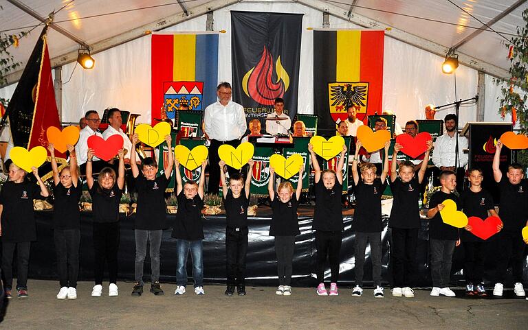 Kinder der Kinderfeuerwehr bedanken sich bei den Feuerwehrleuten mit einem Lied für ihren Einsatz:
'Ihr seid da, wenn Häuser ganz im Flammen stehen, Ihr seid die, die für uns durch das Feuer gehen. Immer da, wenn wir den Notruf wählen...Darum möchten wir Euch einfach Danke sagen, Feuerwehr, Feuerwehr, Danke.' Im Hintergrund die Musikkapelle Spiesheim. Kinder der Kinderfeuerwehr bedanken sich bei den Feuerwehrleuten mit einem Lied für ihren Einsatz:
'Ihr seid da, wenn Häuser ganz im Flammen stehen, Ihr seid die, die für uns durch das Feuer gehen. Immer da, wenn wir den Notruf wählen...Darum möchten wir Euch einfach Danke sagen, Feuerwehr, Feuerwehr, Danke.' Im Hintergrund die Musikkapelle Spiesheim.