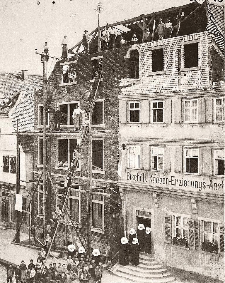 1902 kaufte das Bischöfliche Ordinariat neben der bestehenden Erziehungsanstalt Hauptstraße 65 das Nachbaranwesen Nummer 63, riss das Gebäude ab und errichtete einen Anbau. Das Foto zeigt die Bauarbeiter beim Richtfest und unten die Stern-Schwestern mit den Knaben. 1902 kaufte das Bischöfliche Ordinariat neben der bestehenden Erziehungsanstalt Hauptstraße 65 das Nachbaranwesen Nummer 63, riss das Gebäude ab und errichtete einen Anbau. Das Foto zeigt die Bauarbeiter beim Richtfest und unten die Stern-Schwestern mit den Knaben.