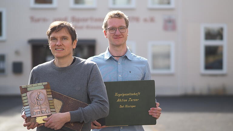 Georg Pickel (links) und Sebastian Häfner (rechts) posieren mit Fotobüchern und Urkunden vor dem Gebäude des TSV Bad Kissingen - Georg Pickel (links) und Sebastian Häfner (rechts) posieren mit Fotobüchern und Urkunden vor dem Gebäude des TSV Bad Kissingen Georg Pickel (links) und Sebastian Häfner (rechts) posieren mit Fotobüchern und Urkunden vor dem Gebäude des TSV Bad Kissingen - Georg Pickel (links) und Sebastian Häfner (rechts) posieren mit Fotobüchern und Urkunden vor dem Gebäude des TSV Bad Kissingen