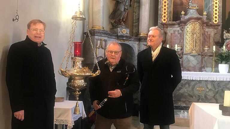 Pfarrer Uwe Hartmann, Sponsor Herbert Müller und Kirchenpfleger Dieter Ofenhitzer bewundern die restaurierte Ampel aus der Gründerzeit.