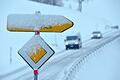 Schnee       -  Neuschnee bedeckt ein Vorfahrtsschild und einen Wegweiser.