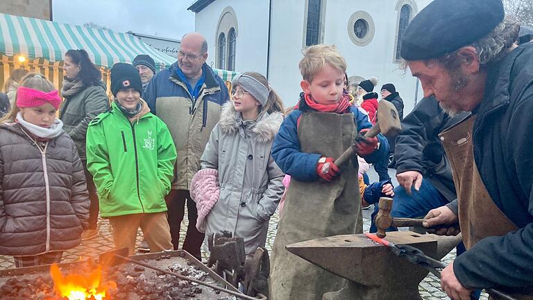 'Kunst in Kinderhand': Ein junger Schmied formt mit Begeisterung das glühende Eisen auf dem Glashütter Weihnachtsmarkt.