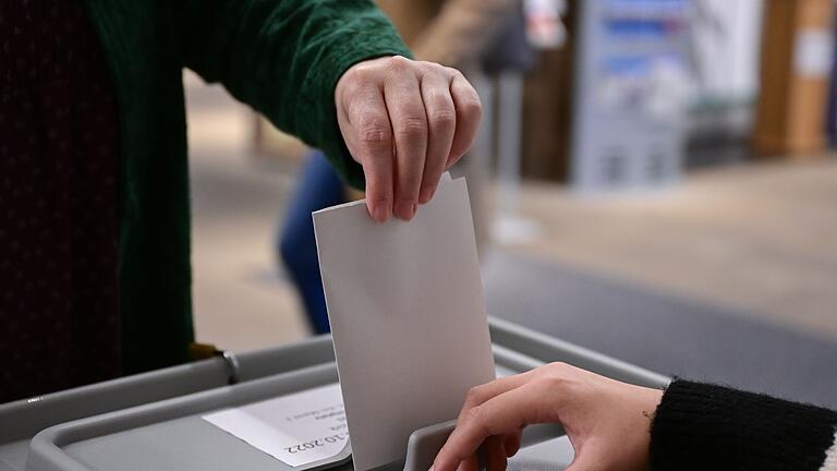 Wahlen.jpeg       -  Ein Wähler steckt bei einer Wahl seinen Wahlzettel in eine Urne.