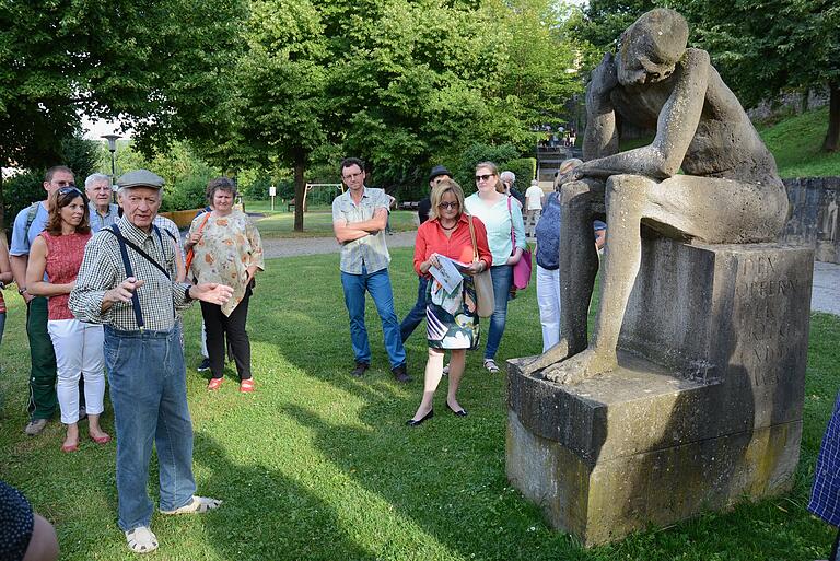 Wilhelm Uhlig 2016 bei einer Führung in Bad Neustadt mit seiner Skulptur 'Der Denkende' am Mahnmal für die Opfer der Weltkriege.