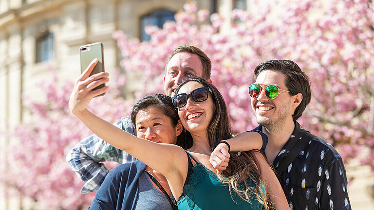 Zahlreiche Menschen tummeln sich am Ostersonntag (17.04.22) im Hofgarten der Residenz in Würzburg. Durch die in voller Pracht stehende Kirschblüte wirkt der Garten besonders schön.