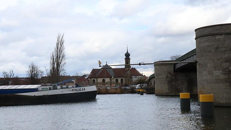 Dieses Frachtschiff fährt in der richtigen Spur unter der Alten Mainbrücke in Kitzingen. Kommt es dennoch von der Fahrrinne ab, kann es die Brückenbögen nicht mehr rammen. Der neue Anprallschutz in Form der gelb gekennzeichneten Stahlrohre verhindert das.&nbsp;