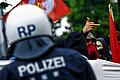 Unbeliebte Freunde und Helfer: Ein vermummter Aktivist der Blockupy-Bewegung zeigt auf diesem Archivbild vom 31. Mai in Frankfurt am Main den nahen Polizisten den Mittelfinger.