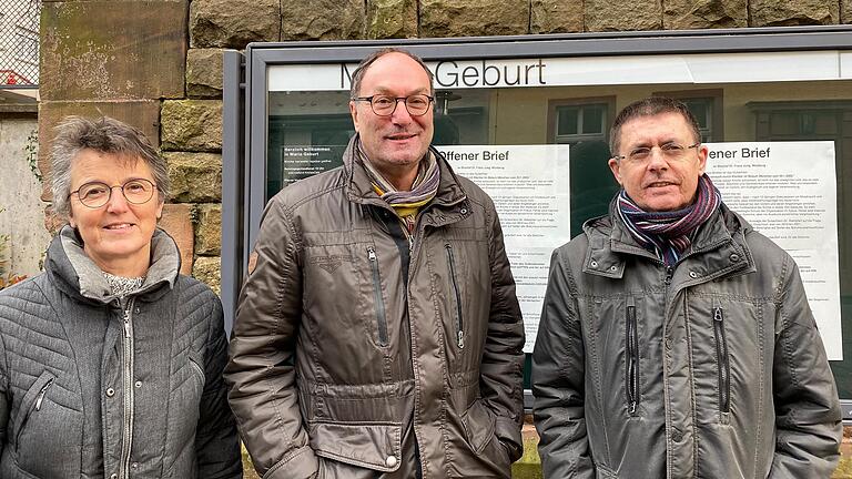 Die Kirchenvorstandsmitglieder der Gemeinde Maria Geburt in Aschaffenburg-Schweinheim: Christine Brumhard, Albert Loy und Joachim Klein. Im Schaukasten haben sie den Offenen Brief an Bischof Jung veröffentlicht.