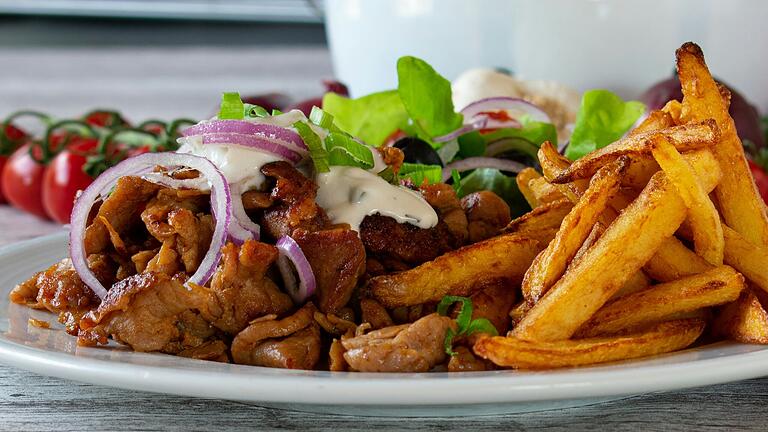 Typisch griechisches Essen: Gyros mit Pommes Frites und frischem Salat mit Zwiebeln und Tomaten.