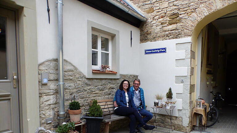 Es ist geschafft! Nach jahrelanger Arbeit sitzen Susanne Baur und Dieter Ludwig im Hof ihres Traumhauses, am sogenannten 'Dieter Ludwig PLatz' wie ein von Freunden geschenktes Straßenschild über ihnen zeigt.