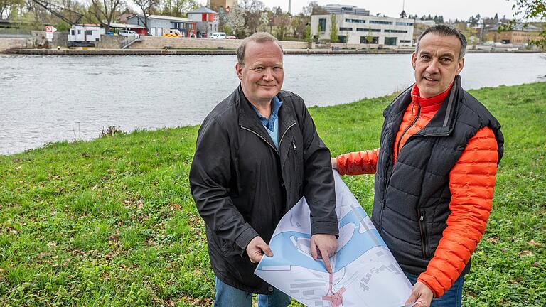 Di­p­lom-In­ge­ni­eur Christian Rehrmann vom Ingenieurbüro Nippert-Rehrmann (links) und der Vorsitzende des Kreisverbandes des Handelsverbandes in Schweinfurt, Axel Schöll, zeigen den Plan für eine neue dritte Mainbrücke in Schweinfurt.