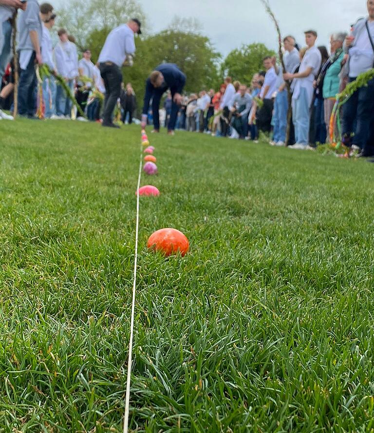 Mit einer Schnur werden die Abstände von den Eierlauf Bürgermeister unter den Augen der Zuschauer festgelegt. Insgesamt 75 Eier werden im Abstand von circa 62 cm für den Sammler ausgelegt.