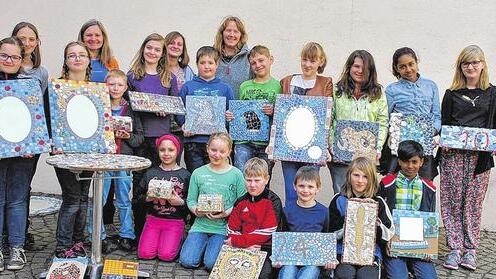 Stolz auf die Ergebnisse: Die Kursteilnehmer, hier mit den Kursleiterinnen Alexandra Laske (Mitte) und Rita van Eckert (hinten, Zweite von links), zeigen ihre schönsten Produkte. Sogar ein Tisch wurde mit einem Mosaik verziert.