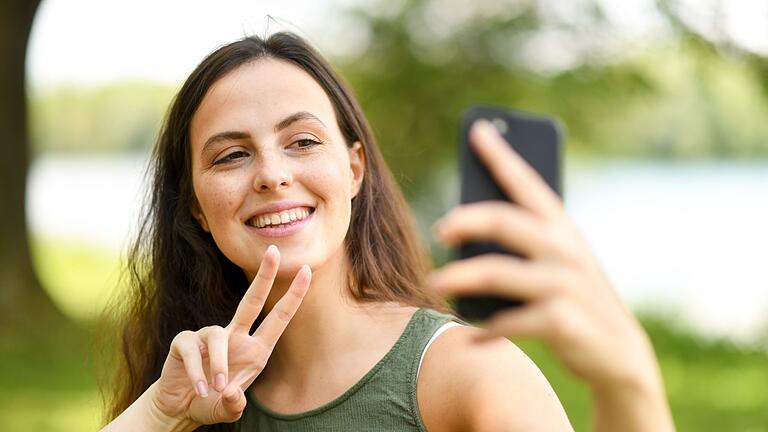 Frau fotografiert Selfie       -  Digitale Urlaubsgrüße: Knapp die Hälfte der Befragten nutzt dafür Social Media wie Instagram oder Facebook.