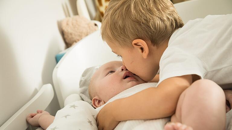 Ein Junge gibt seinem kleinen Bruder einen Kuss       -  In den ersten sechs Lebensmonaten ist das Risiko für schwere RSV-Verläufe besonders hoch.