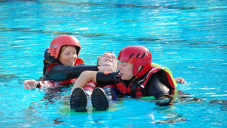 Die angehenden Notfallsanitäter Anne Krönert und David Kraus trainieren im Schwimmbad Rettungstechniken, ihr Kollege Sebastian Sämmer spielt Patient. Foto: Daniel Ostertag / BRK Würzburg