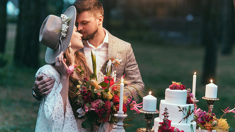 beautiful couple on wedding standing near cake and candles       -  Tipis, Traumfänger, satte Beerentöne: Noch einmal den warmen Glanz der Sonne auskosten, der Natur nahe sein - eine Trauung im Indian Summer-Style hat einen ganz besonderen Spirit.