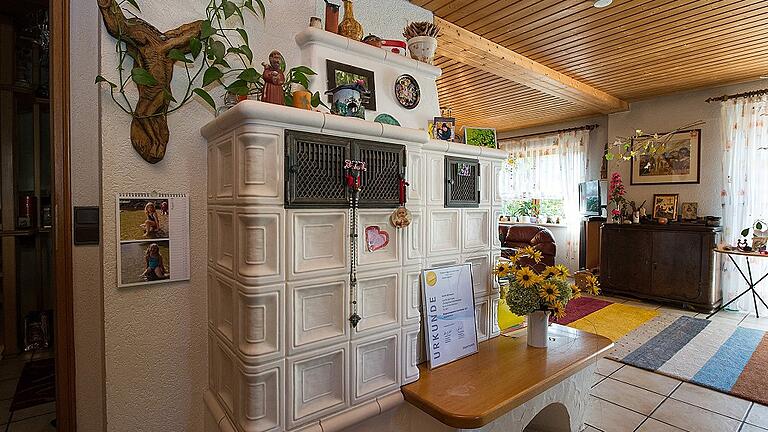 Aufgrund der neuen guten Dämmung muss im Winter der Kachelofen im Wohnzimmer kaum noch angeschürt werden. Platz hat dort auch die Urkunde des Bürgerenergiepreises Unterfranken 2017, den die Familie Bärhausen für ihr ökologisches Gesamtkonzept erhielt.