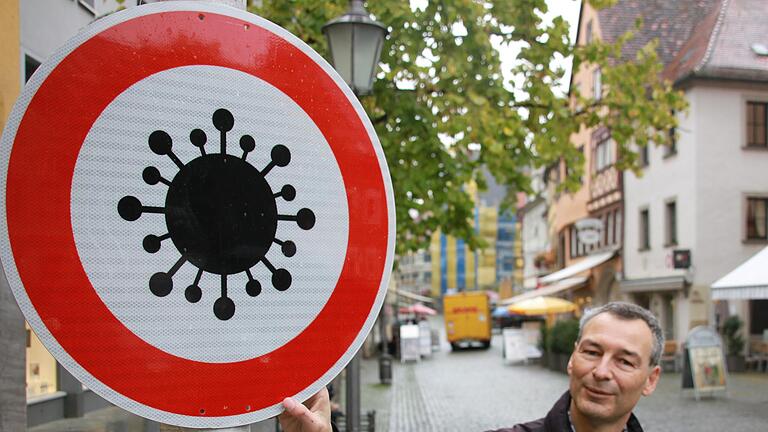 Corona lässt nicht locker: Der Würzburger Künstler Sieghart Böhme hängt sein 'Virus-Verbotsschild' am Eingang zum Ktzinger Marktplatz auf. Corona lässt nicht locker: Der Würzburger Künstler Sieghart Böhme hängt sein 'Virus-Verbotsschild' am Eingang zum Ktzinger Marktplatz auf.
