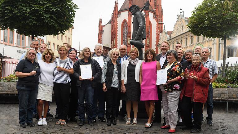 Die Würzburger Marktleute posieren vor dem Häckerbrunnen für ein Gruppenbild, nachdem der Landesverband der Marktkaufleute und Schausteller einige von ihnen für besondere Verdienste ausgezeichnet hat.&nbsp;