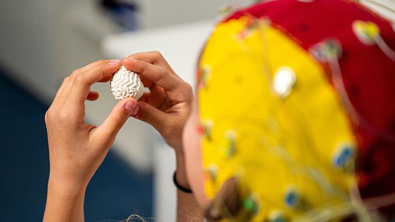 100 Jahre EEG       -  Eine Probandin trägt eine EEG-Haube mit Elektroden für die Messung.