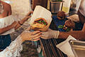 Food truck burger       -  Woman hand reaching for a burger at food truck. Closeup of food truck salesman serving burger to female customer.