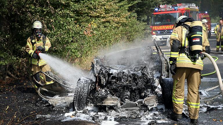 Feuerwehrleute löschen das Auto, das bei einem Raubüberfall in Alzenau als Fluchtfahrzeug genutzt und von den Tätern angezündet worden sein soll. Feuerwehrleute löschen das Auto, das bei einem Raubüberfall in Alzenau als Fluchtfahrzeug genutzt und von den Tätern angezündet worden sein soll.