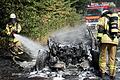 Feuerwehrleute löschen das Auto, das bei einem Raubüberfall in Alzenau als Fluchtfahrzeug genutzt und von den Tätern angezündet worden sein soll.