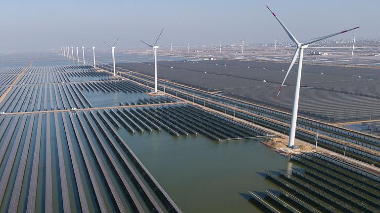 Solar- und Windanlagen in China       -  Windräder drehen sich auf einem riesigen Solarpark in China. (Archivbild)