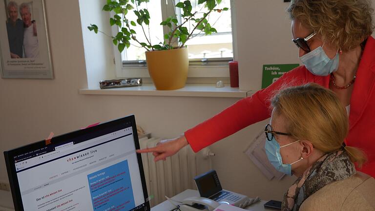 Die Leiterin der Lohrer Volkshochschule, Susanne Duckstein, und Mitarbeiterin Gabriele Reiser bereiten Plakate vor für Veranstaltungen von vhs.wissen live im Mai.