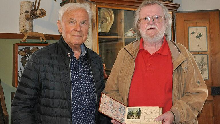 Peter Büdel  (rechts) mit dem Stammbuch in den Händen und Museumsleiter Eduard Stenger im Lohrer Schulmuseum.