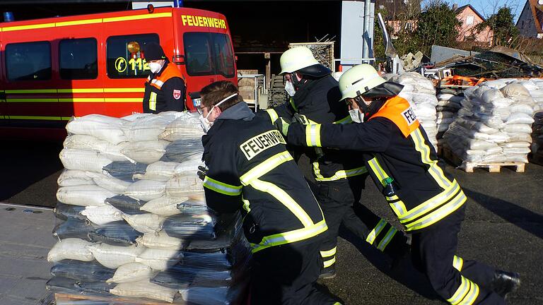 Fast eine Tonne wiegt die Palette mit Sandsäcken, die Feuerwehrleute an den Einsatzort schieben.