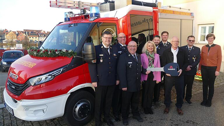 Die Feuerwehrführungskräfte, Landrätin Tamara Bischof (Mitte) und Pfarrerin Eva Thelen (rechts) sind dabei, als Kommandant Joachim Müller den symbolischen Fahrzeugschlüssel von Bürgermeister Harald Kopp überreicht bekommt.