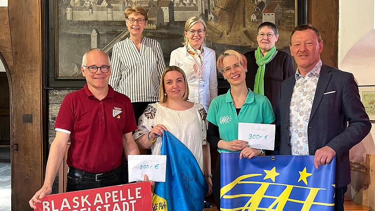 Robert Schmitt (Leiter der Blaskapelle Giebelstadt-Sulzdorf), Olga Skopets (Organisatorin von Hilfstransporten in die Ukraine), Astrid Eitschberger (Dirigentin des Collegium Musicum Iuvenale Ochsenfurt), Peter Juks (Bürgermeister der Stadt Ochsenfurt); hintere Reihe: Renate Glauth und Fabienne Wanderer (stellvertretend für alle Klassenlehrerinnen der 2. Klassen der Grundschule Ochsenfurt), Sigrid Schäfer (Leiterin der Gruppe „Veehnklang im Liederkranz“) bei der Spendenübergabe. Nicht mit auf dem Bild ist André Mabiala, erster Vorstand von Mbonda Lokito Kongo/Konshasa Kinderhilfe e.V.